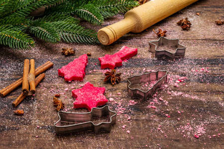 Cooking red ginger cookies. Traditional Christmas pastries. Festive culinary background. Fir tree, spices, cookie cutters, raw dough, rolling pin, wooden boards, close upの写真素材