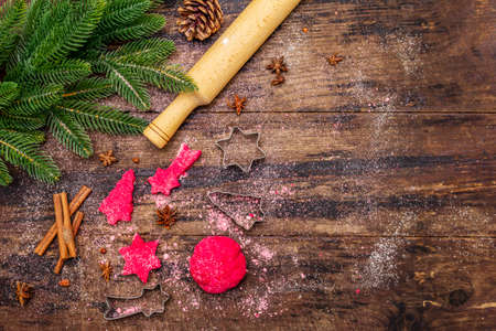 Cooking red ginger cookies. Traditional Christmas pastries. Festive culinary background. Fir tree, spices, cookie cutters, raw dough, rolling pin, wooden boards, copy space, top viewの写真素材
