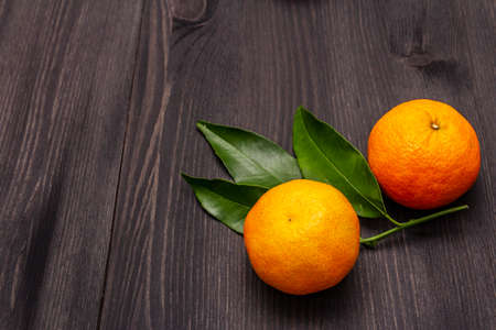 Fresh ripe tangerines with leaves. New Year or Christmas wooden background. Festive good mood concept, copy spaceの写真素材