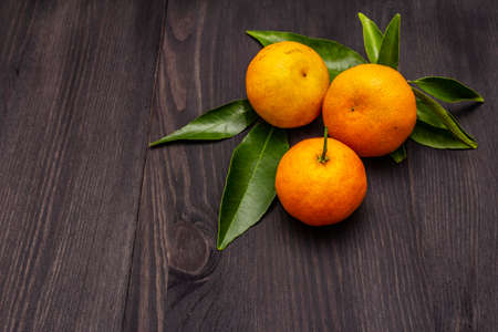 Fresh ripe tangerines with leaves. New Year or Christmas wooden background. Festive good mood concept, copy spaceの写真素材