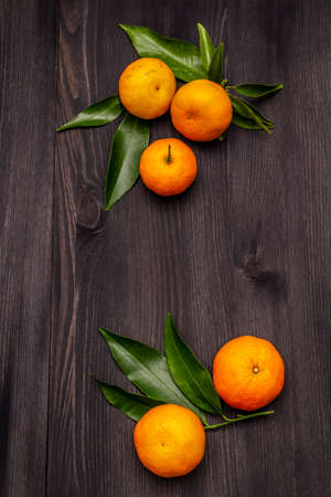 Fresh ripe tangerines with leaves. New Year or Christmas wooden background. Festive good mood concept, copy space, top viewの写真素材