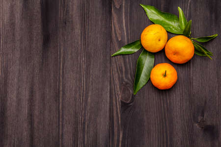 Fresh ripe tangerines with leaves. New Year or Christmas wooden background. Festive good mood concept, copy space, top viewの写真素材