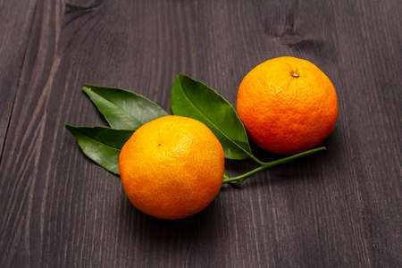 Fresh ripe tangerines with leaves. New Year or Christmas wooden background. Festive good mood concept, close upの写真素材