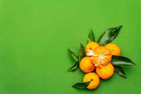 Ripe tangerines with leaves. Fresh fruits isolated on green background, copy space, top viewの写真素材
