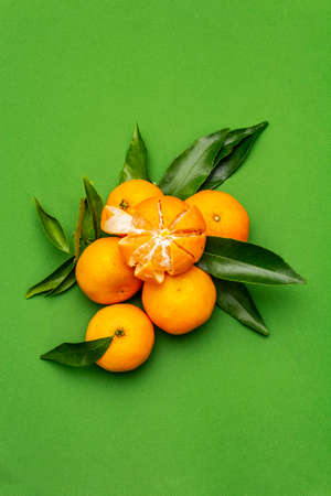 Ripe tangerines with leaves. Fresh fruits isolated on green background, copy space, top viewの写真素材