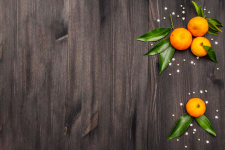 Fresh ripe tangerines with leaves and sprinkles. New Year or Christmas wooden background. Festive good mood concept, copy space, top viewの写真素材