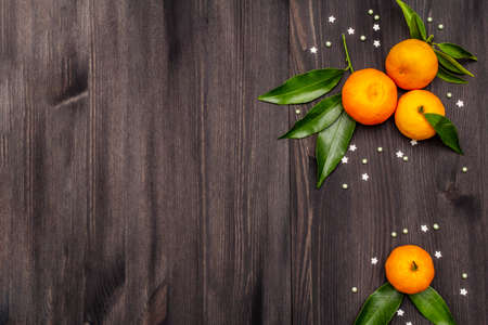 Fresh ripe tangerines with leaves and sprinkles. New Year or Christmas wooden background. Festive good mood concept, copy space, top viewの写真素材