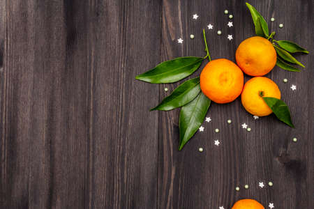 Fresh ripe tangerines with leaves and sprinkles. New Year or Christmas wooden background. Festive good mood concept, copy space, top viewの写真素材