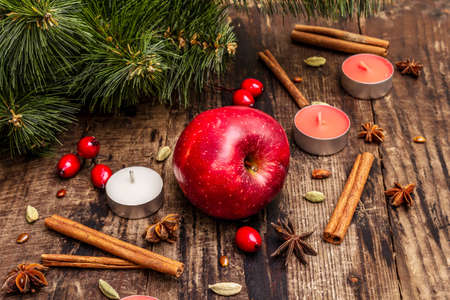 Spirit Christmas background. New Year tree, fresh apple, cinnamon, dog rose, candles, cardamom, star anise. Nature decorations, vintage wooden boards, close upの写真素材