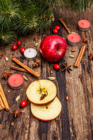 Spirit Christmas background. New Year tree, fresh apple, cinnamon, dog rose, candles, cardamom, star anise. Nature decorations, vintage wooden boards, close upの写真素材