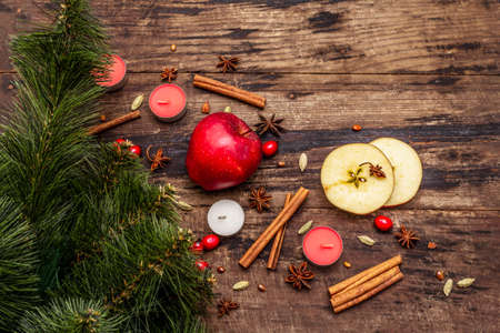 Spirit Christmas background. New Year tree, fresh apple, cinnamon, dog rose, candles, cardamom, star anise. Nature decorations, vintage wooden boards, copy space, top viewの写真素材
