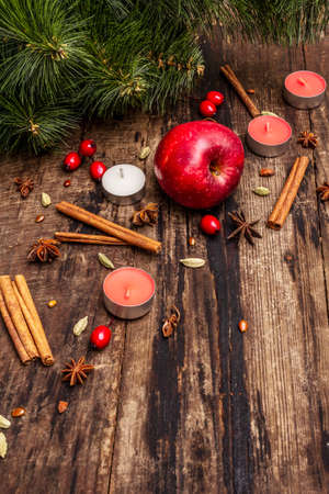 Spirit Christmas background. New Year tree, fresh apple, cinnamon, dog rose, candles, cardamom, star anise. Nature decorations, vintage wooden boards, copy spaceの写真素材