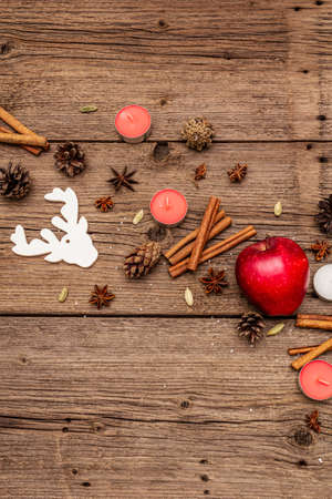 Spirit Christmas background. Apple, candles, spices, deer, cones. Nature New Year decorations, vintage wooden boards, copy space, top viewの写真素材