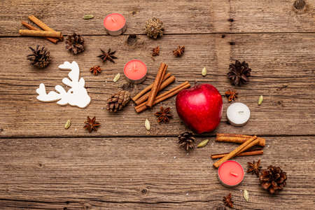 Spirit Christmas background. Apple, candles, spices, deer, cones. Nature New Year decorations, vintage wooden boards, copy space, top viewの写真素材