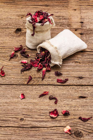 Dry hibiscus petals. Ingredient for cooking hot tea. Healthy food and self-care concept. Old wooden boards backgrounds, copy spaceの写真素材