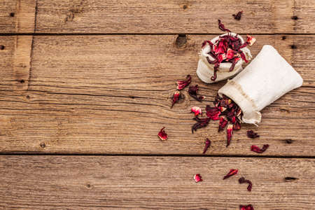 Dry hibiscus petals. Ingredient for cooking hot tea. Healthy food and self-care concept. Old wooden boards backgrounds, copy space, top viewの写真素材