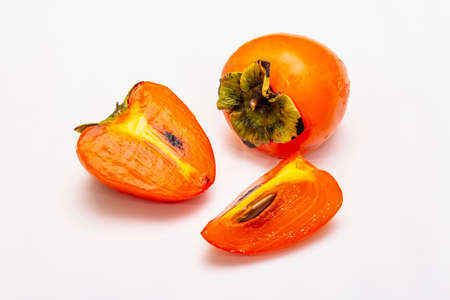 Ripe single persimmon. Fresh whole fruit, half sliced, seeds. Isolated on white background, close upの写真素材