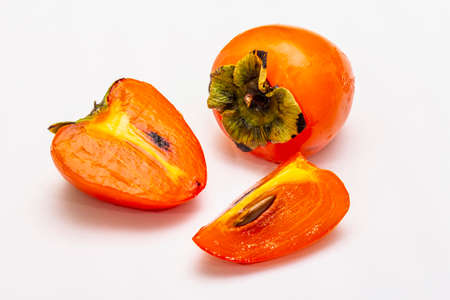 Ripe single persimmon. Fresh whole fruit, half sliced, seeds. Isolated on white background, close upの写真素材