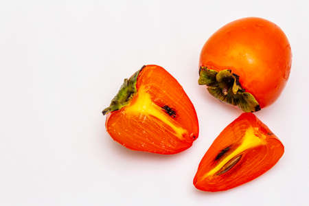 Ripe single persimmon. Fresh whole fruit, half sliced, seeds. Isolated on white background, copy space, top viewの写真素材