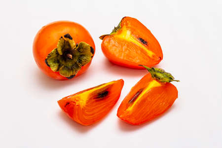 Ripe single persimmon. Fresh whole fruit, half sliced, seeds. Isolated on white background, close upの写真素材