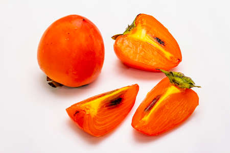 Ripe single persimmon. Fresh whole fruit, half sliced, seeds. Isolated on white background, close upの写真素材