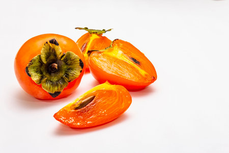 Ripe single persimmon. Fresh whole fruit, half sliced, seeds. Isolated on white background, copy...