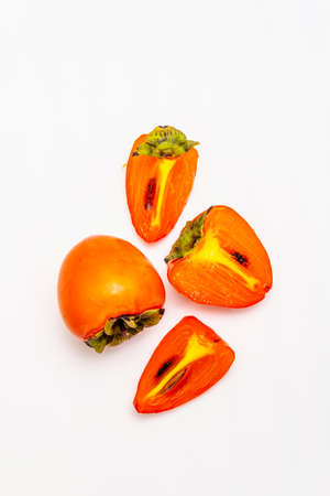 Ripe single persimmon. Fresh whole fruit, half sliced, seeds. Isolated on white background, copy space, top viewの写真素材