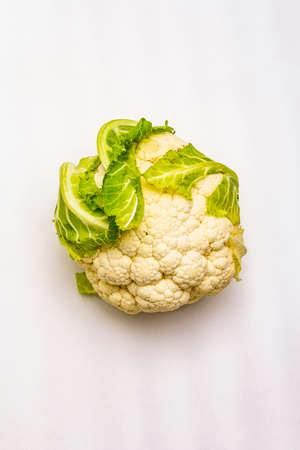 Ripe single cauliflower. Fresh whole head of cabbage, green leaves. Isolated on white background, copy space, top viewの写真素材