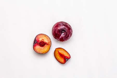 Ripe large purple plums. Fresh whole fruits, half sliced, seeds. Isolated on white background, copy space, top viewの写真素材