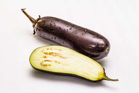 Ripe single eggplant. Fresh whole and half vegetable. Isolated on white background, close upの写真素材