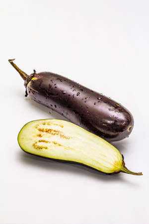 Ripe single eggplant. Fresh whole and half vegetable. Isolated on white background, copy spaceの写真素材