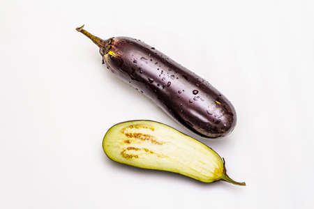 Ripe single eggplant. Fresh whole and half vegetable. Isolated on white background, copy space, top viewの写真素材