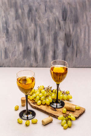 Wine glasses, fresh grapes and corks on wooden chopping board. Wine bar, winery, wine tasting concept. Stone concrete background, copy spaceの写真素材