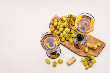 Wine glasses, fresh grapes and corks on wooden chopping board. Wine bar, winery, wine tasting concept. Stone concrete background, copy space, top viewの写真素材