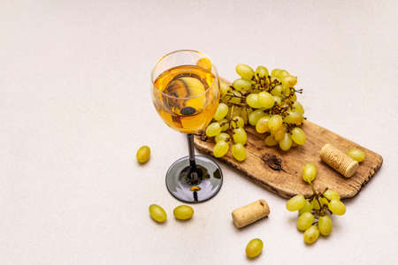 Wine glass, fresh grapes and corks on wooden chopping board. Wine bar, winery, wine tasting concept. Stone concrete background, copy spaceの写真素材