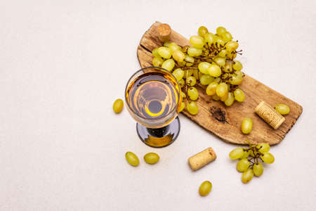 Wine glass, fresh grapes and corks on wooden chopping board. Wine bar, winery, wine tasting concept. Stone concrete background, copy space, top viewの写真素材
