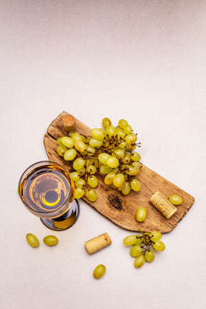 Wine glass, fresh grapes and corks on wooden chopping board. Wine bar, winery, wine tasting concept. Stone concrete background, copy space, top viewの写真素材