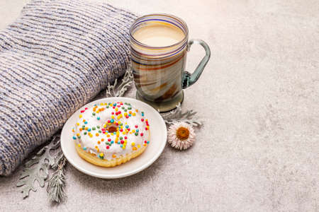 Hot coffee with a donut. Winter drink for a good mood with sweater, leaves and flowers. Old wood plank background, copy spaceの写真素材