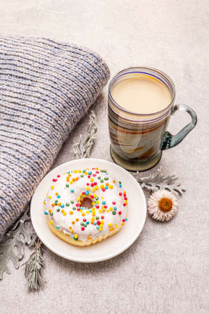 Hot coffee with a donut. Winter drink for a good mood with sweater, leaves and flowers. Old wood plank background, close upの写真素材