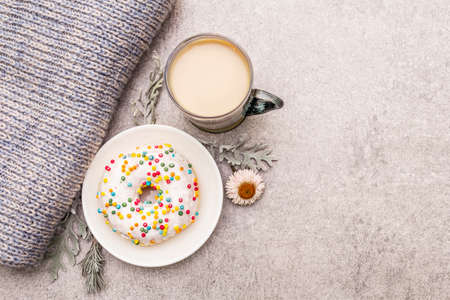 Hot coffee with a donut. Winter drink for a good mood with sweater, leaves and flowers. Old wood plank background, copy space, top viewの写真素材
