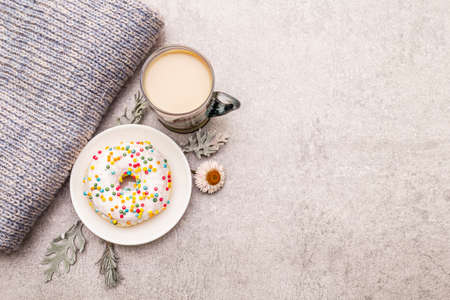Hot coffee with a donut. Winter drink for a good mood with sweater, leaves and flowers. Old wood plank background, copy space, top viewの写真素材
