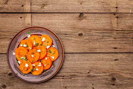 Roasted pumpkin with salted cheese and herbs. Healthy vegetarian snack. Vintage napkin, wooden boards background, copy space, top viewの写真素材