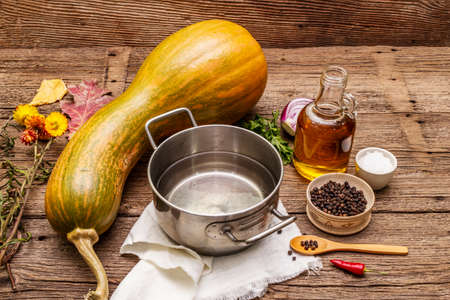 Ingredients for cooking pumpkin cream soup. Fresh vegetables, water, oil, spices. Vintage wood backgroundの写真素材