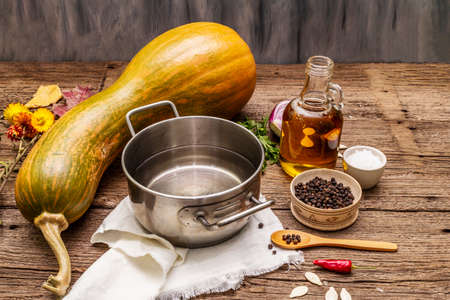 Ingredients for cooking pumpkin cream soup. Fresh vegetables, water, oil, spices. Vintage wood backgroundの写真素材