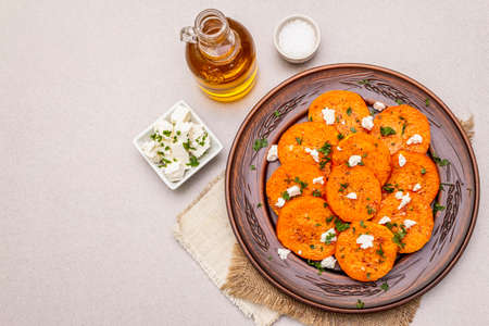 Roasted pumpkin with salted cheese and herbs. Healthy vegetarian snack. Vintage napkins, stone concrete background, copy space, top viewの写真素材