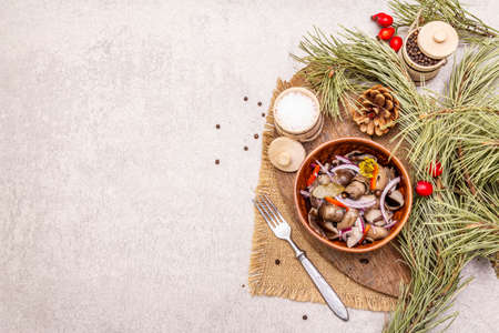 Pickled or fermented mushrooms. Traditional Christmas snack. New Year Festive cutlery. Evergreen pine, cone, spices, chopping board. Stone concrete background copy space top viewの写真素材