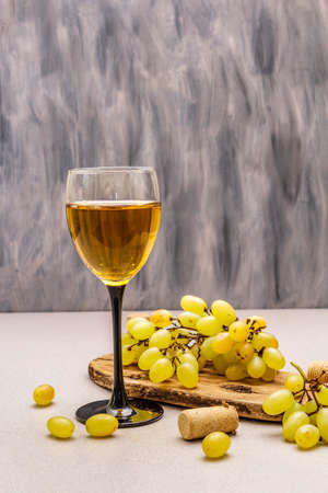 Wine glass, fresh grapes and corks on wooden chopping board. Wine bar, winery, wine tasting concept. Stone concrete background, copy spaceの写真素材