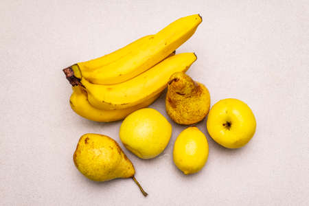 Assorted bright yellow fruits. Fresh banana, pear, apple, lemon. Harvest on a stone background, close up, to viewの写真素材