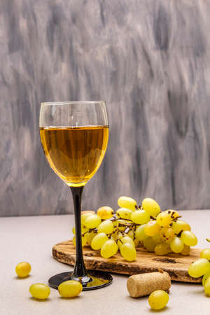Wine glass, fresh grapes and corks on wooden chopping board. Wine bar, winery, wine tasting concept. Stone concrete background, copy space, close upの写真素材