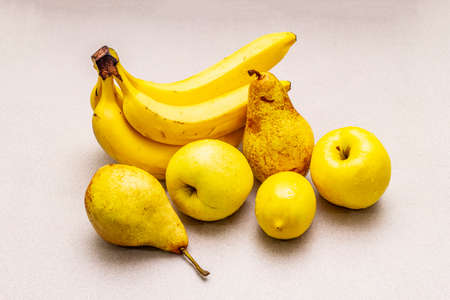 Assorted bright yellow fruits. Fresh banana, pear, apple, lemon. Harvest on a stone background, close upの写真素材